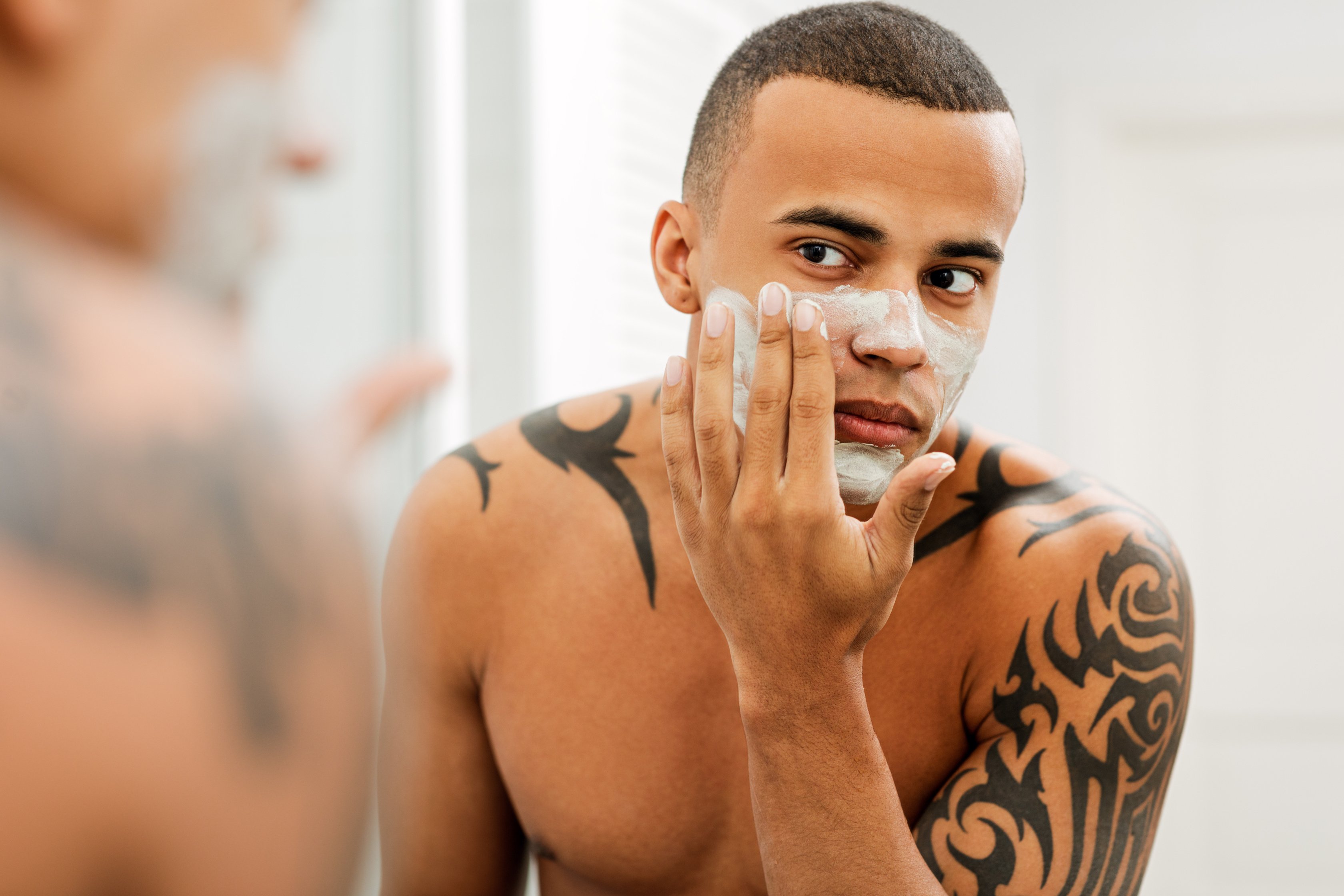 Young man applying anti-aging cream on his face